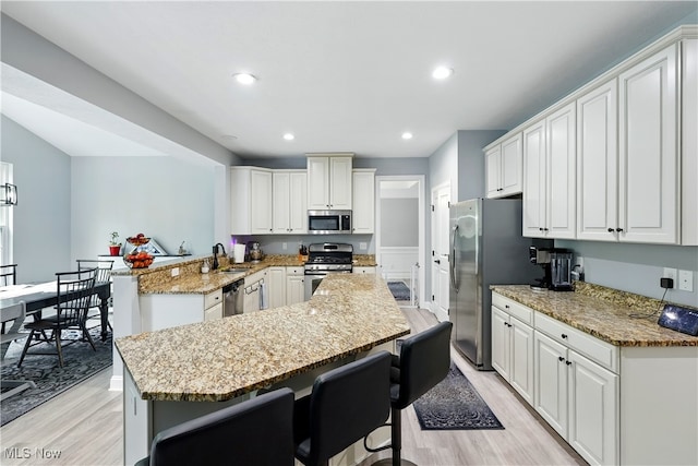 3425 Eryn Pl, Hudson, OH 44236 - kitchen featuring appliances with stainless steel finishes, light wood-type flooring, a breakfast bar, a kitchen island, and light stone countertops