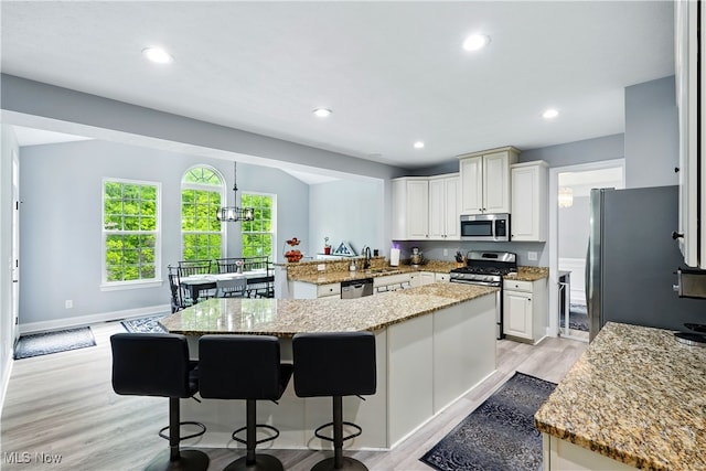 3425 Eryn Pl, Hudson, OH 44236 - kitchen featuring stainless steel appliances, light stone countertops, a kitchen island, light wood-style floors, and a breakfast bar