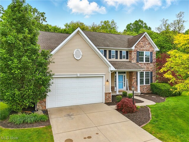 3425 Eryn Pl, Hudson, OH 44236 - view of front of house with stone siding, driveway, an attached garage, a front yard, and roof with shingles