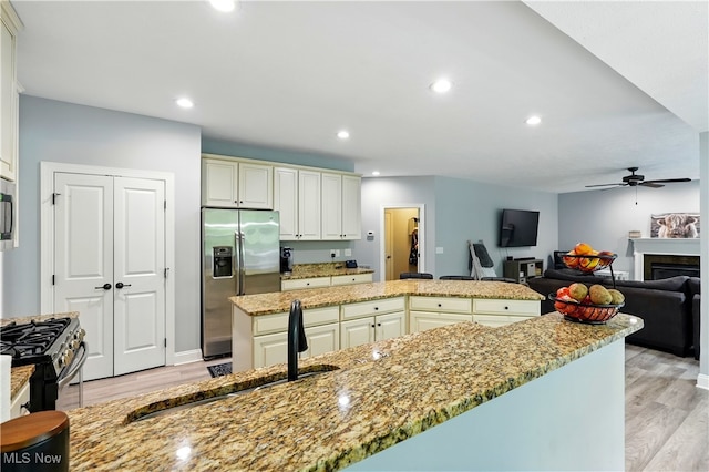 3425 Eryn Pl, Hudson, OH 44236 - kitchen featuring stainless steel appliances, a center island, light wood-style flooring, ceiling fan, and light stone countertops