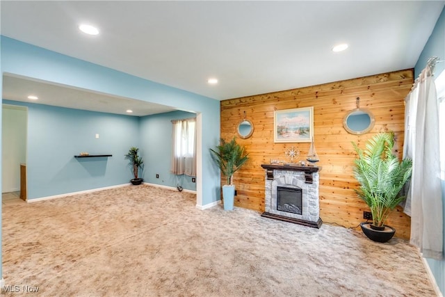 4944 Coleman Dr, Akron, OH 44319 - unfurnished living room featuring carpet floors, a stone fireplace, recessed lighting, wooden walls, and baseboards