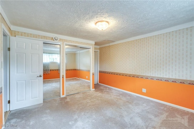 4944 Coleman Dr, Akron, OH 44319 - unfurnished bedroom with a textured ceiling, wallpapered walls, carpet floors, two closets, and baseboards