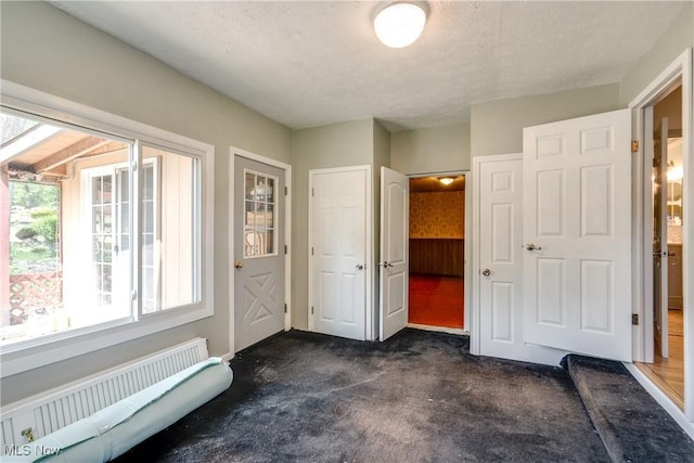 4944 Coleman Dr, Akron, OH 44319 - foyer entrance with radiator heating unit, dark carpet, a textured ceiling, and baseboards