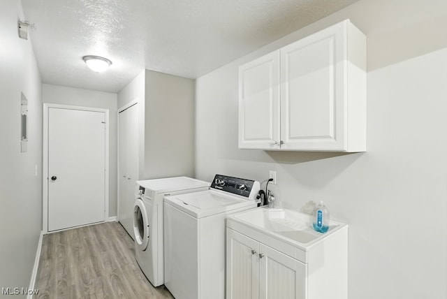 17682 Eastbrook Trl, Chagrin Falls, OH 44023 - laundry area with washing machine and dryer, light wood-style flooring, cabinet space, a textured ceiling, and baseboards