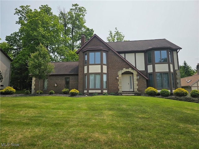 6671 Queens Way N, Royalton, OH 44133 - tudor house with a chimney, a front lawn, brick siding, a shingled roof, and stucco siding