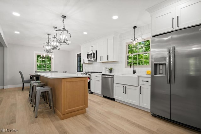 6730 Stone Rd, Medina, OH 44256 - kitchen with stainless steel appliances, a kitchen island, backsplash, light wood-style floors, and a sink