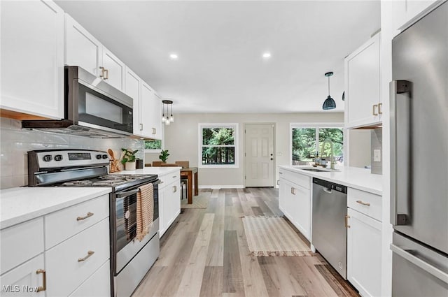 5679 Wilson Mills Rd, Highland Heights, OH 44143 - kitchen with appliances with stainless steel finishes, light wood-style floors, white cabinetry, light countertops, and hanging light fixtures