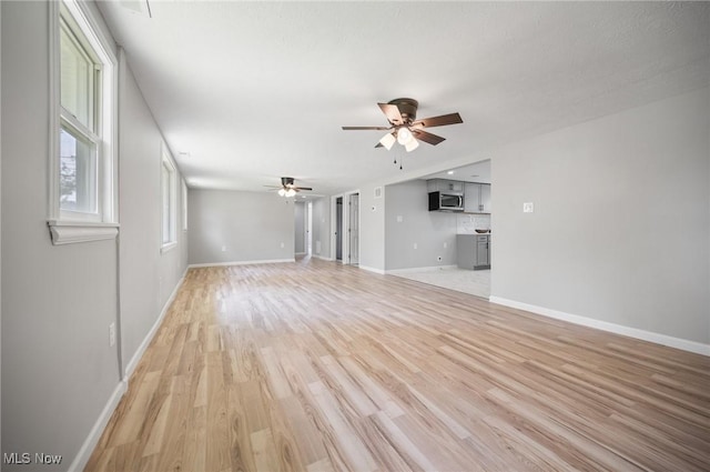 403 Palomino Ct, Lagrange, OH 44050 - unfurnished living room featuring ceiling fan, light wood-style flooring, and baseboards