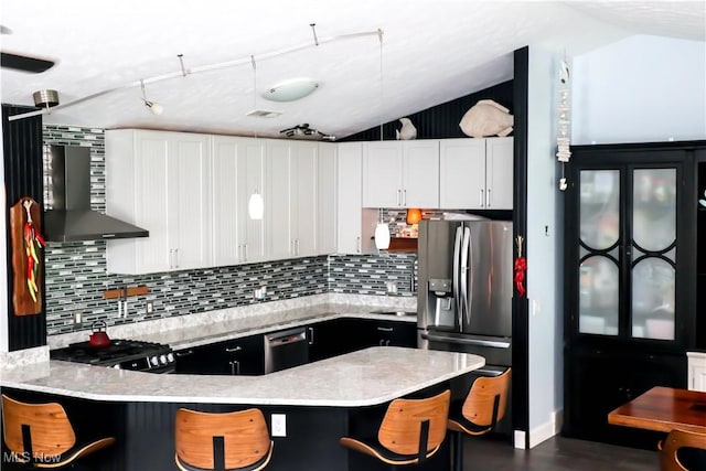 682 2nd St Unit 1, Fairport Harbor, OH 44077 - kitchen featuring appliances with stainless steel finishes, wall chimney range hood, decorative backsplash, a peninsula, and vaulted ceiling