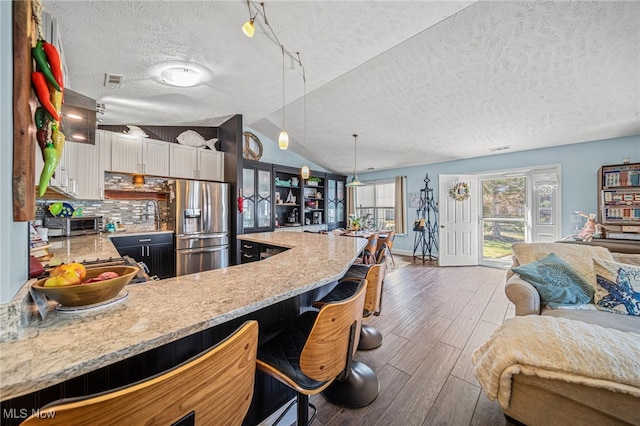682 2nd St Unit 1, Fairport Harbor, OH 44077 - kitchen with stainless steel fridge with ice dispenser, open floor plan, wood finished floors, white cabinets, and tasteful backsplash