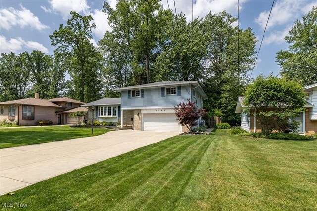 5046 Devon Dr, North Olmsted, OH 44070 - tri-level home with a garage, concrete driveway, a front lawn, and brick siding