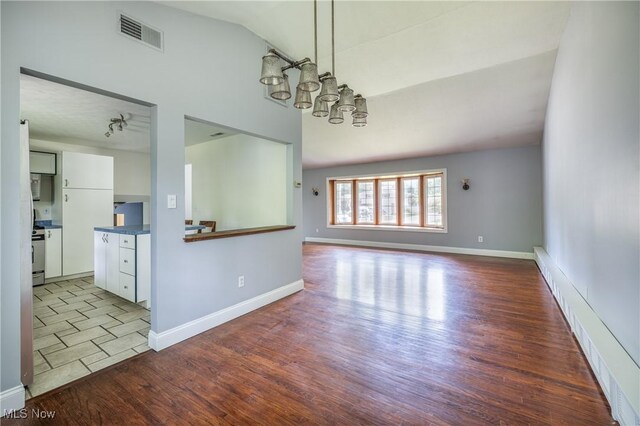 5046 Devon Dr, North Olmsted, OH 44070 - unfurnished living room featuring lofted ceiling, wood finished floors, a chandelier, and baseboards