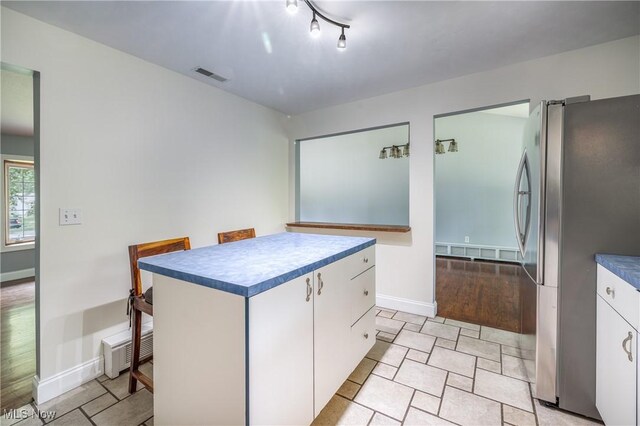 5046 Devon Dr, North Olmsted, OH 44070 - kitchen with freestanding refrigerator, white cabinets, baseboards, dark countertops, and a kitchen island