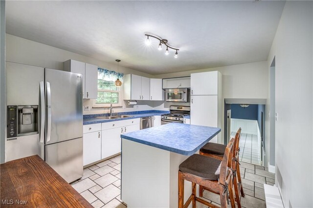 5046 Devon Dr, North Olmsted, OH 44070 - kitchen featuring stainless steel appliances, a sink, a breakfast bar, a kitchen island, and white cabinets