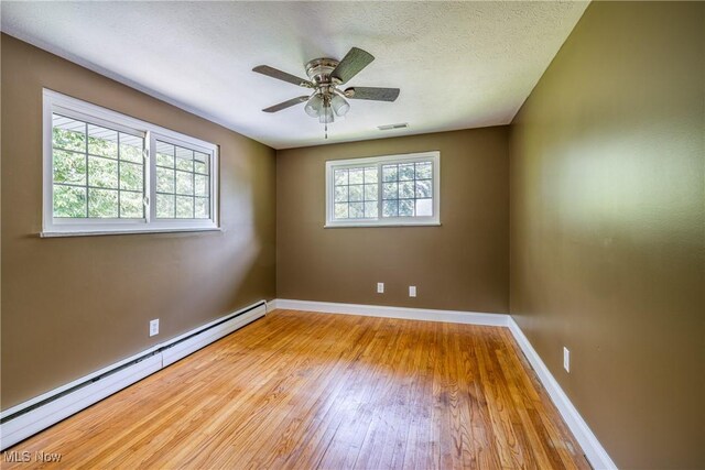 5046 Devon Dr, North Olmsted, OH 44070 - empty room featuring a baseboard heating unit, hardwood / wood-style floors, baseboards, a ceiling fan, and a textured ceiling