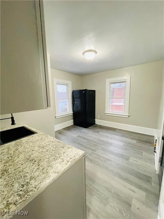 2511 4th St NW, Canton, OH 44708 - kitchen with freestanding refrigerator, a sink, light wood-type flooring, baseboards, and light stone countertops