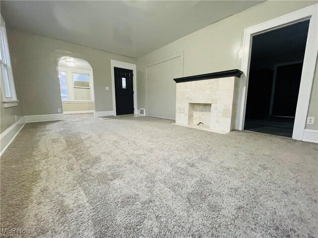 2511 4th St NW, Canton, OH 44708 - unfurnished living room with carpet, a tiled fireplace, arched walkways, and baseboards