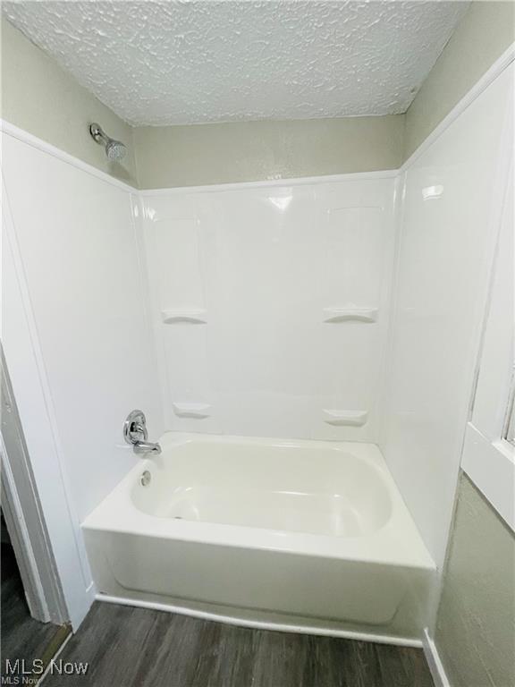 2511 4th St NW, Canton, OH 44708 - bathroom with wood finished floors, a textured ceiling, and shower / washtub combination