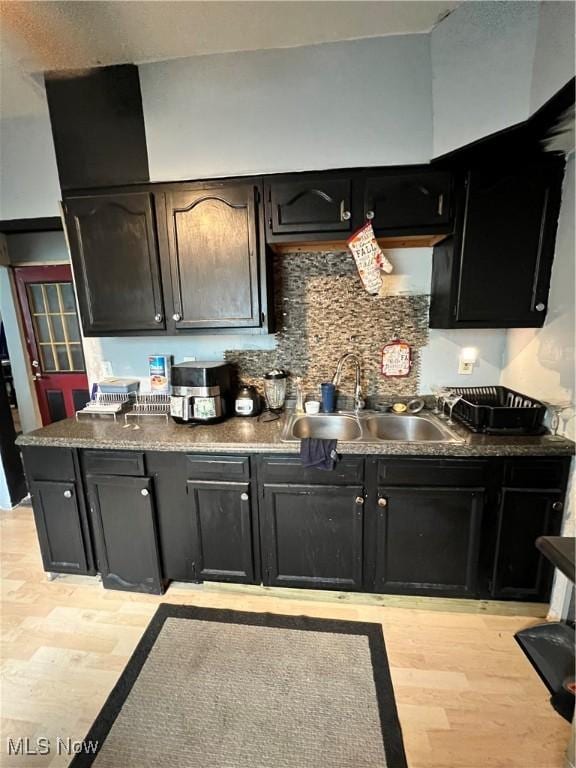 3524 E 139th St, Cleveland, OH 44120 - kitchen featuring a sink, light wood-style flooring, tasteful backsplash, dark countertops, and dark cabinets