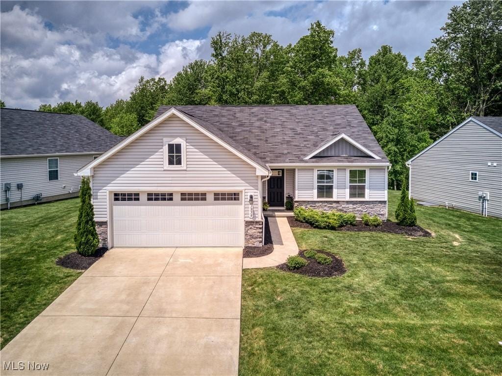 1579 Leslie Dr, Streetsboro, OH 44241 - traditional-style home with stone siding, a garage, a front yard, driveway, and a shingled roof