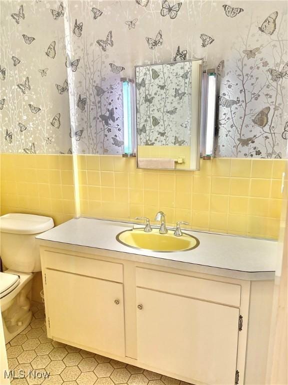 15959 Ridge Rd, North Royalton, OH 44133 - bathroom featuring wallpapered walls, vanity, toilet, tile walls, and tile patterned flooring