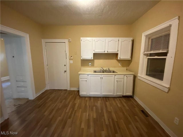 3454 E 118th St, Cleveland, OH 44120 - kitchen featuring a sink, white cabinetry, dark wood-style flooring, baseboards, and a textured ceiling