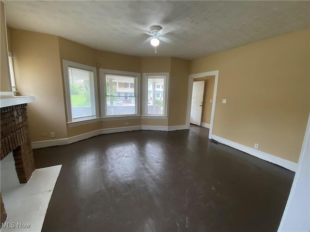 3454 E 118th St, Cleveland, OH 44120 - unfurnished living room featuring ceiling fan, baseboards, a fireplace, dark wood finished floors, and a textured ceiling
