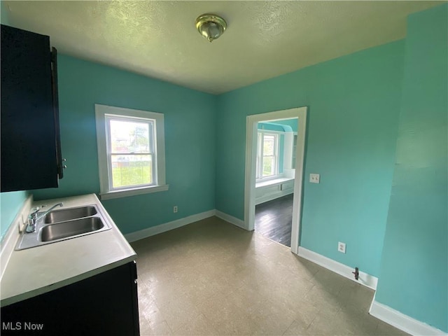 3454 E 118th St, Cleveland, OH 44120 - kitchen featuring a sink, light countertops, baseboards, a textured ceiling, and light floors