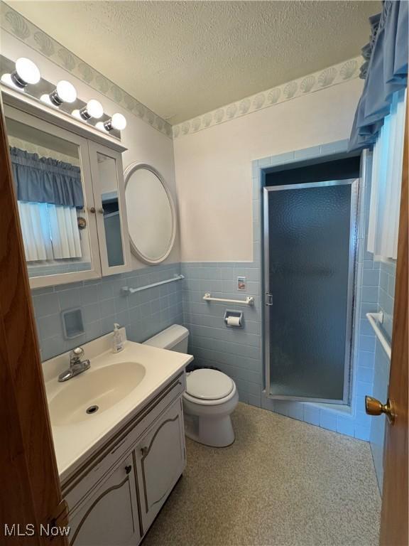 9 James Ct, Parkersburg, WV 26105 - bathroom featuring tile walls, a shower stall, vanity, toilet, and a textured ceiling