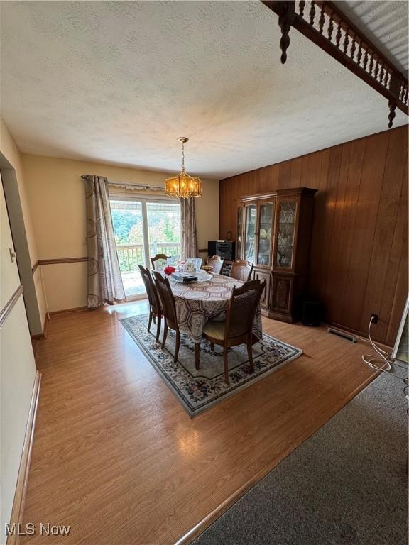 9 James Ct, Parkersburg, WV 26105 - dining room featuring a chandelier, light wood-style floors, baseboards, a textured ceiling, and wood walls