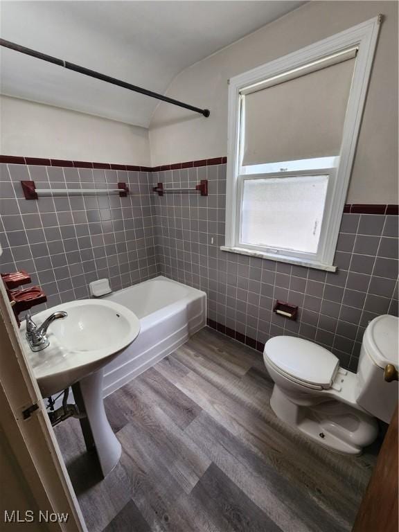 1039 Argonne Rd, South Euclid, OH 44121 - bathroom featuring tile walls, toilet, wood finished floors, washtub / shower combination, and wainscoting