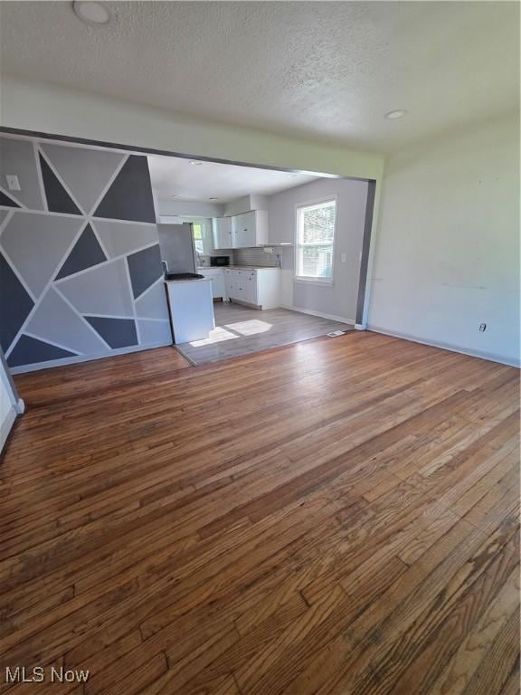 3801 Archmere Ave, Old Brooklyn, OH 44109 - unfurnished living room with wood finished floors, a textured ceiling, and baseboards