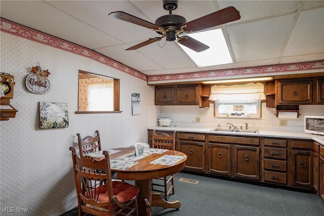 1303 28th St, Vienna, WV 26105 - kitchen featuring a sink, a ceiling fan, healthy amount of natural light, light countertops, and wallpapered walls