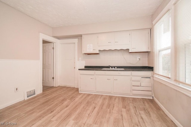 4101 E 64th St, Cleveland, OH 44105 - kitchen with dark countertops, light wood finished floors, a sink, and a textured ceiling