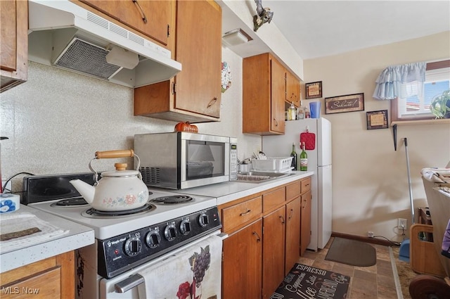 962 N Market St, Lisbon, OH 44432 - kitchen with white appliances, under cabinet range hood, light countertops, and brown cabinets
