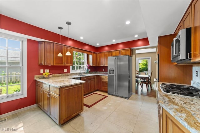 177 N Park Dr, Aurora, OH 44202 - kitchen with appliances with stainless steel finishes, a peninsula, light stone counters, brown cabinets, and decorative light fixtures