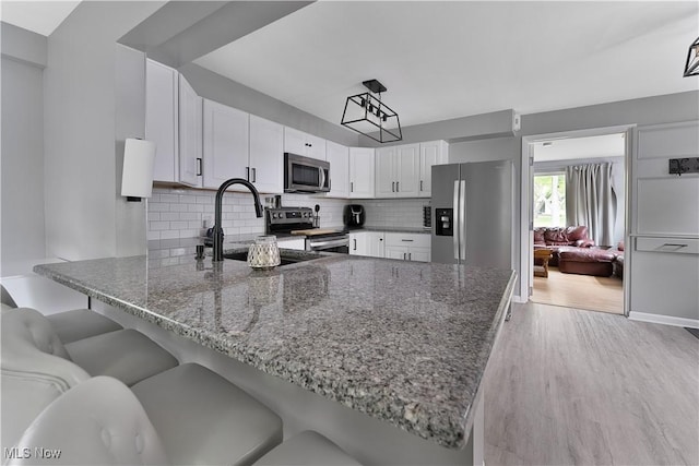 1094 Jessie Ave, Kent, OH 44240 - kitchen with appliances with stainless steel finishes, a peninsula, dark stone counters, and tasteful backsplash