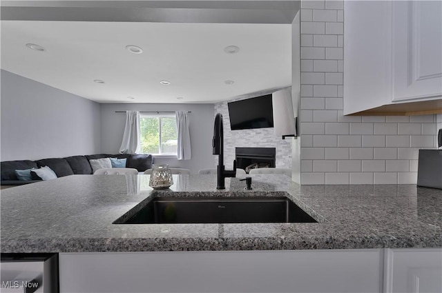 1094 Jessie Ave, Kent, OH 44240 - kitchen featuring a sink, open floor plan, a large fireplace, dark stone counters, and tasteful backsplash