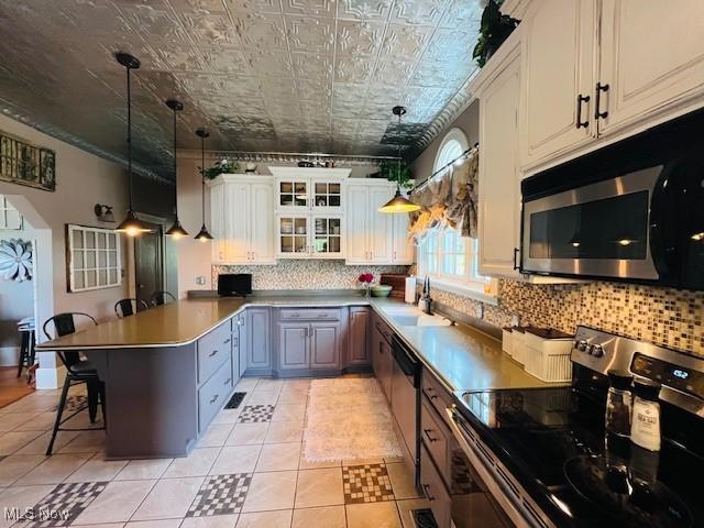 161 W Main St, New Concord, OH 43762 - kitchen with appliances with stainless steel finishes, a sink, backsplash, a peninsula, and a breakfast bar