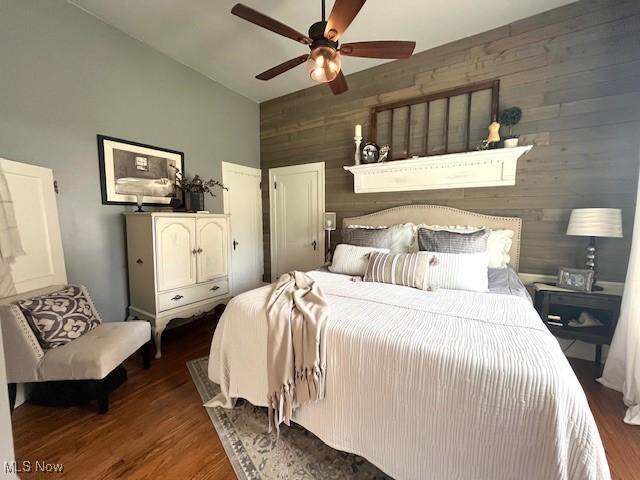 161 W Main St, New Concord, OH 43762 - bedroom featuring wooden walls, wood finished floors, vaulted ceiling, and ceiling fan