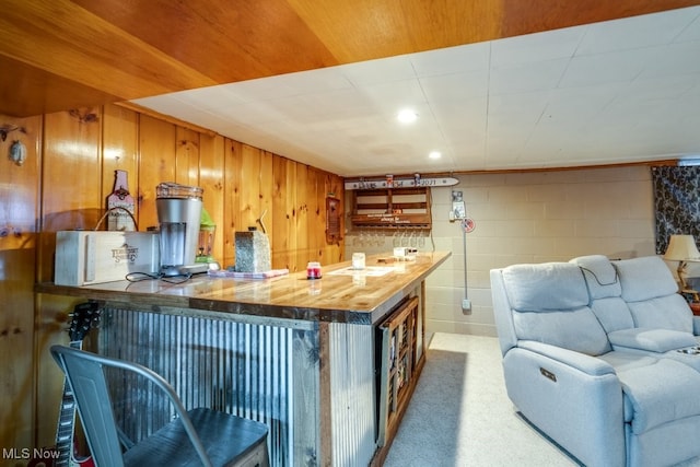 396 2nd St NE, Carrollton, OH 44615 - kitchen with carpet, open floor plan, butcher block countertops, brown cabinetry, and concrete block wall