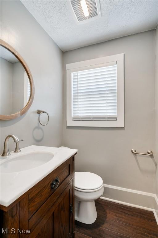 990 Franklin Ave, Salem, OH 44460 - half bathroom with vanity, wood finished floors, toilet, a textured ceiling, and baseboards