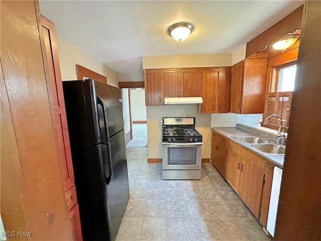 816 Clarendon Ave NW, Canton, OH 44708 - kitchen with stainless steel range with gas stovetop, freestanding refrigerator, a sink, under cabinet range hood, and brown cabinetry
