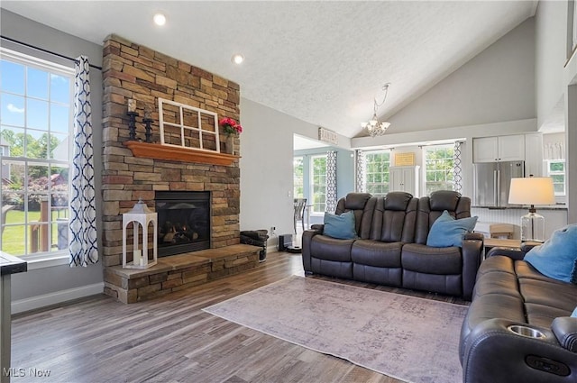 269 Brookledge Ln, Copley, OH 44321 - living area with a chandelier, wood finished floors, high vaulted ceiling, baseboards, and a stone fireplace