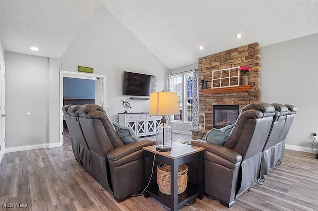 269 Brookledge Ln, Copley, OH 44321 - living area with baseboards, a stone fireplace, wood finished floors, a textured ceiling, and high vaulted ceiling