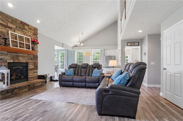 269 Brookledge Ln, Copley, OH 44321 - living room featuring a textured ceiling, baseboards, a chandelier, wood finished floors, and a stone fireplace