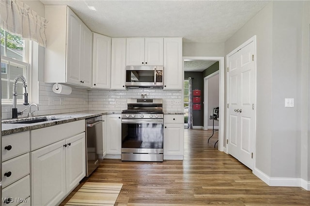 269 Brookledge Ln, Copley, OH 44321 - kitchen with appliances with stainless steel finishes, a sink, decorative backsplash, white cabinetry, and wood finished floors