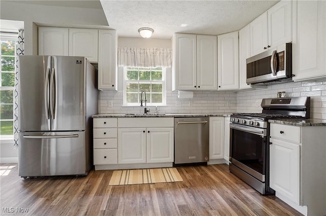 269 Brookledge Ln, Copley, OH 44321 - kitchen with appliances with stainless steel finishes, a sink, dark stone counters, white cabinetry, and a textured ceiling