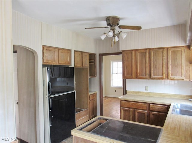 3659 Riedham Rd, Shaker Heights, OH 44120 - kitchen featuring freestanding refrigerator, wallpapered walls, brown cabinetry, light countertops, and a ceiling fan