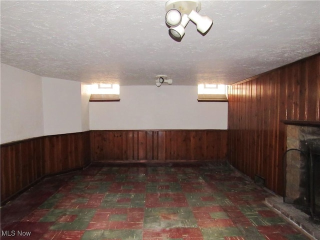 3659 Riedham Rd, Shaker Heights, OH 44120 - basement featuring wooden walls, a fireplace with raised hearth, a textured ceiling, tile patterned floors, and wainscoting